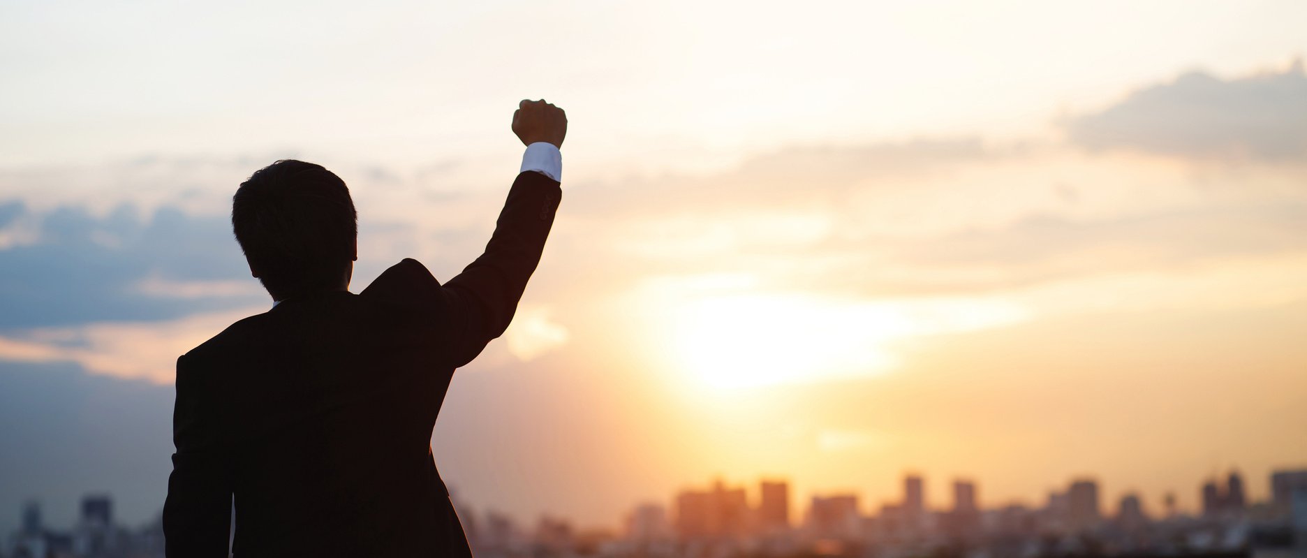 Businessman Raising Hand in Sunset  